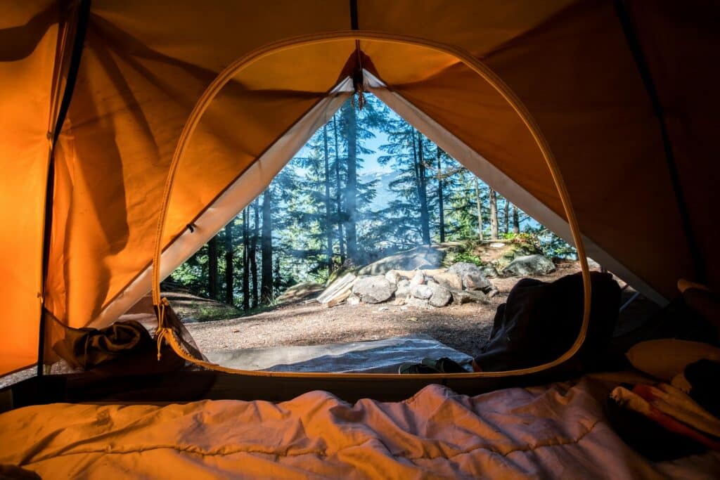 Tente campée au bord d'un lac entouré de montagnes