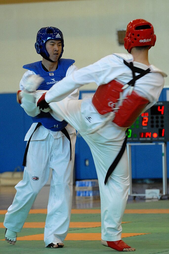 Pratiquants de taekwondo en uniforme dobok, en position de combat, avec une jambe levée pour exécuter un coup de pied impressionnant