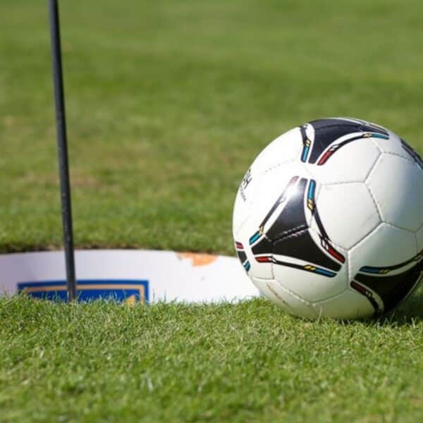 Trou de footgolf soigneusement aménagé sur un terrain de golf, avec le drapeau flottant et un ballon