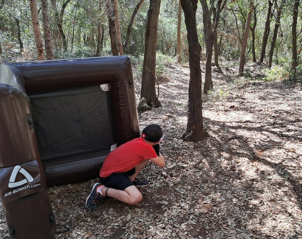 Adolescent en train de se divertir et de profiter d'une partie de laser tag en plein air