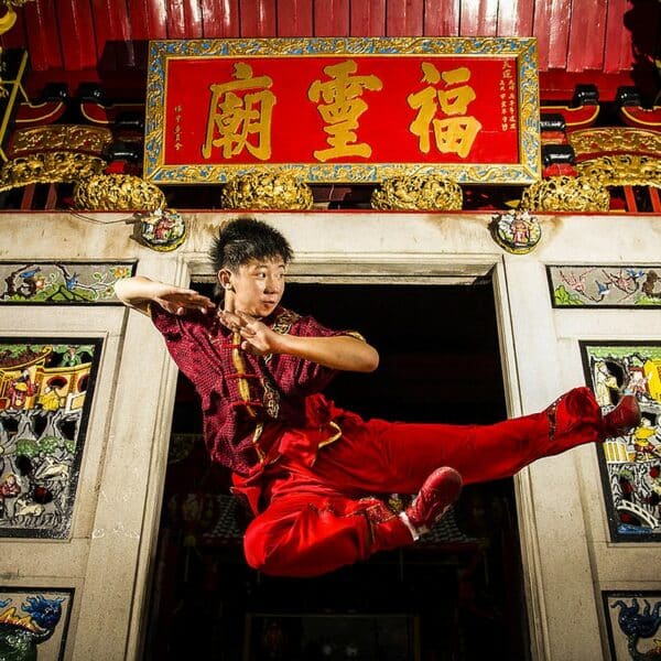 Athlète réalisant une acrobatie aérienne en Wushu, démontrant l’agilité spectaculaire de cet art martial