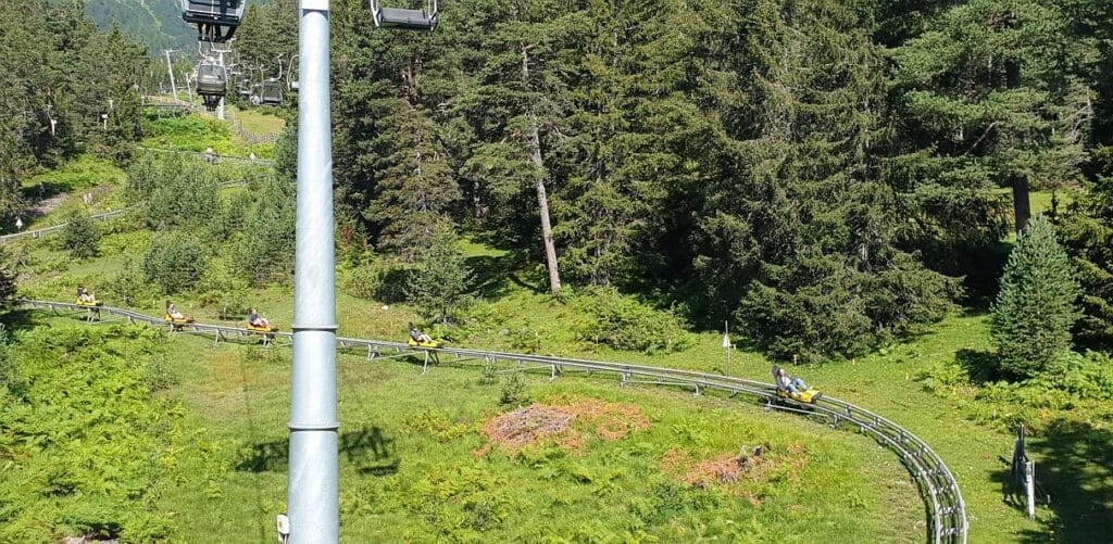 Longue piste de Mountain Luge vue depuis les hauteurs, intégrée dans le paysage naturel