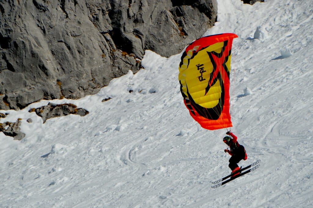 Pratiquant de speedflying glissant sur la neige tout en contrôlant sa mini‑voile