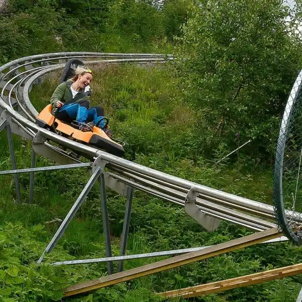 Pratiquant dévalant une piste de Mountain Luge en été, alliant vitesse et sensations de glisse