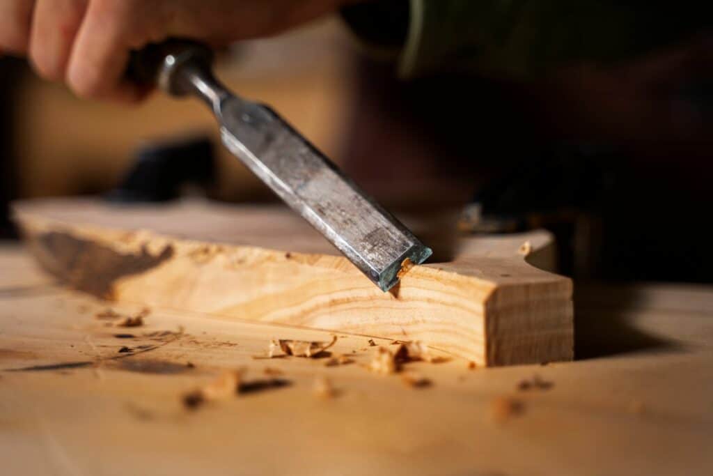 Main tenant un couteau de sculpture pour façonner une figurine en bois